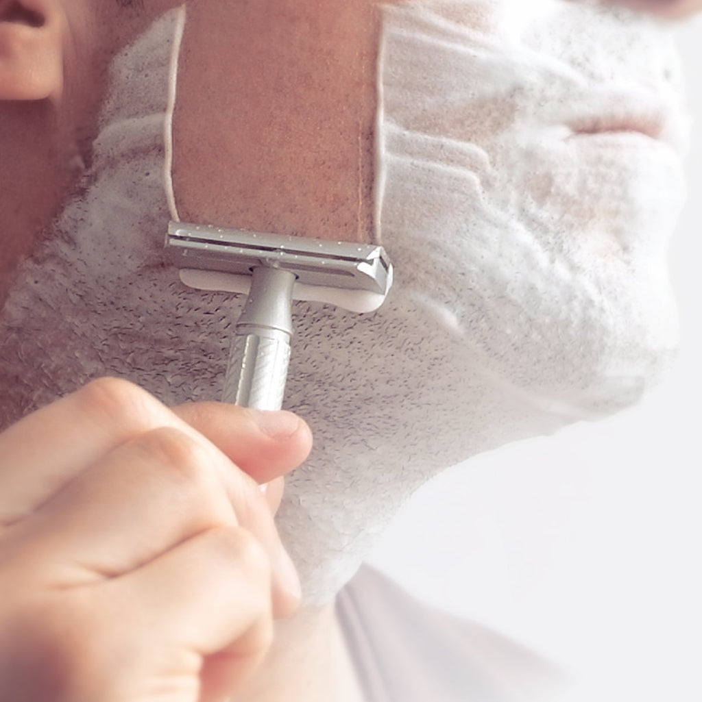 Person shaving with a razor on a white background